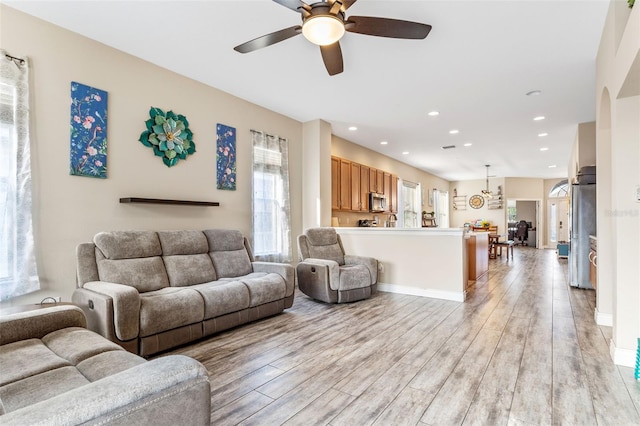 living area with light wood-style flooring, baseboards, a ceiling fan, and recessed lighting