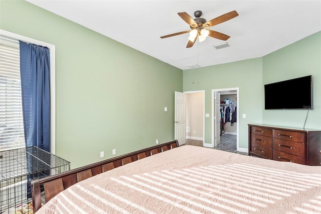 bedroom featuring a ceiling fan, visible vents, baseboards, a closet, and a walk in closet