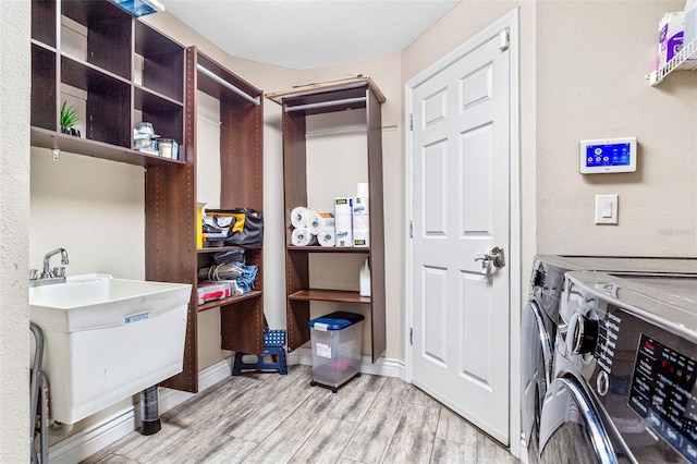 washroom featuring light wood-style flooring, a sink, washer and dryer, laundry area, and baseboards