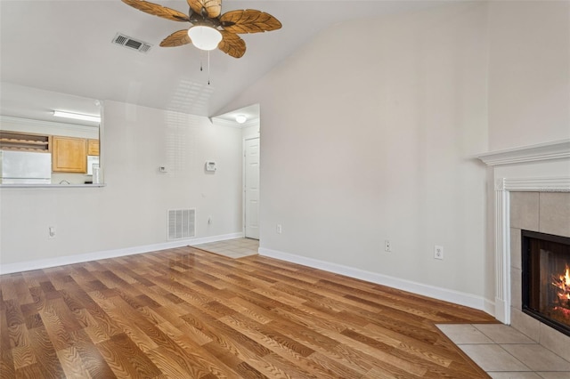 unfurnished living room with light wood-style floors, a fireplace, visible vents, and ceiling fan