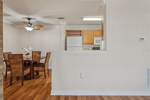 dining room with visible vents, baseboards, ceiling fan, light wood-type flooring, and ornamental molding