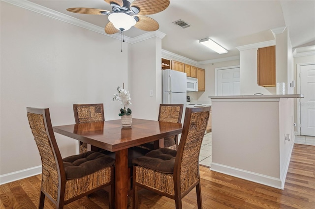 dining area with crown molding and light wood-style floors