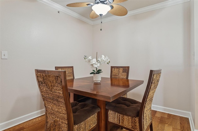 dining space with crown molding, wood finished floors, baseboards, and ceiling fan