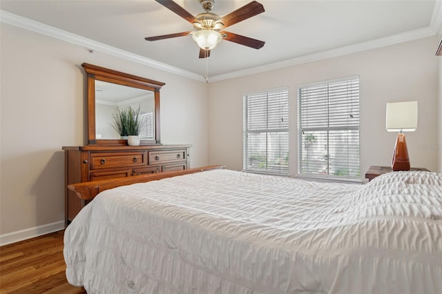 bedroom featuring a ceiling fan, crown molding, baseboards, and wood finished floors