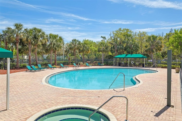 pool featuring a community hot tub, a patio, and fence