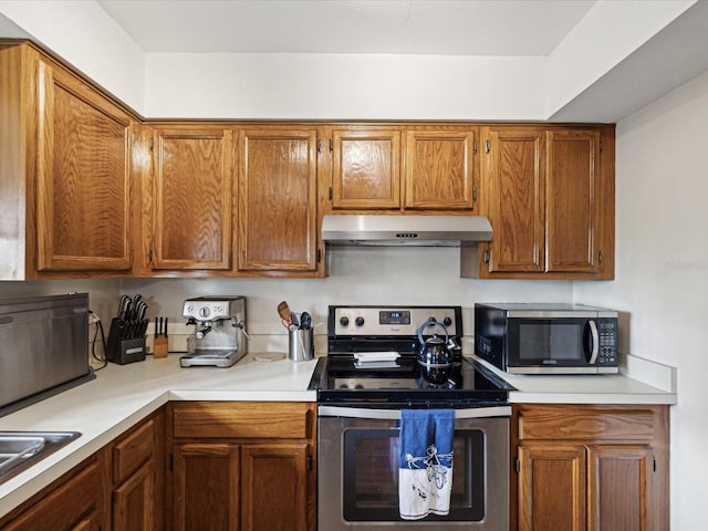 kitchen with light countertops, appliances with stainless steel finishes, brown cabinets, and under cabinet range hood