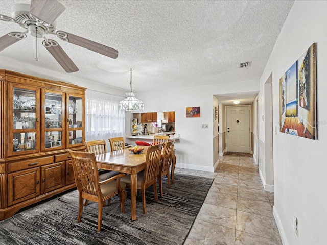 dining area with baseboards, visible vents, ceiling fan, and a textured ceiling