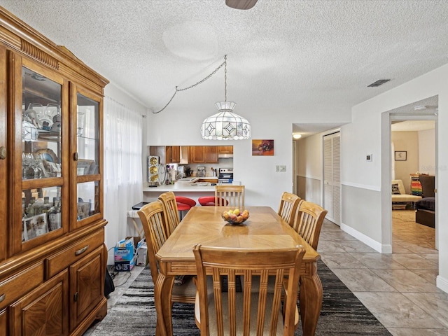 dining area with light tile patterned floors, lofted ceiling, visible vents, a textured ceiling, and baseboards