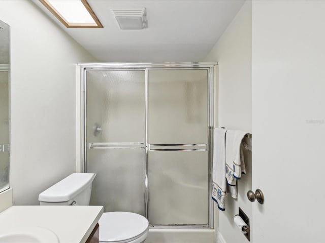 bathroom featuring toilet, a shower with door, visible vents, and vanity