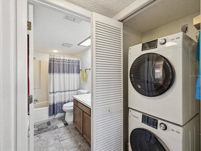 laundry area featuring visible vents, laundry area, a textured ceiling, and stacked washer and clothes dryer