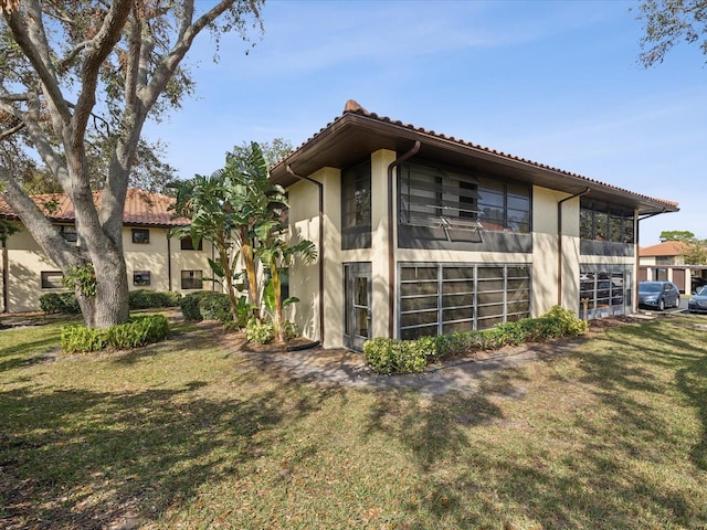 view of home's exterior with stucco siding, a tile roof, and a yard