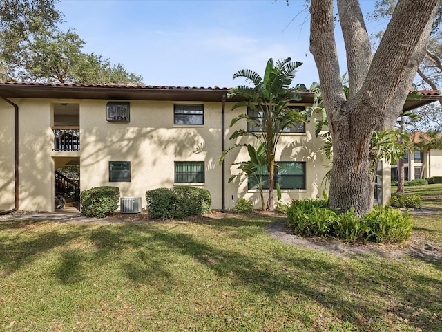 view of home's exterior featuring stairway, a lawn, cooling unit, and stucco siding