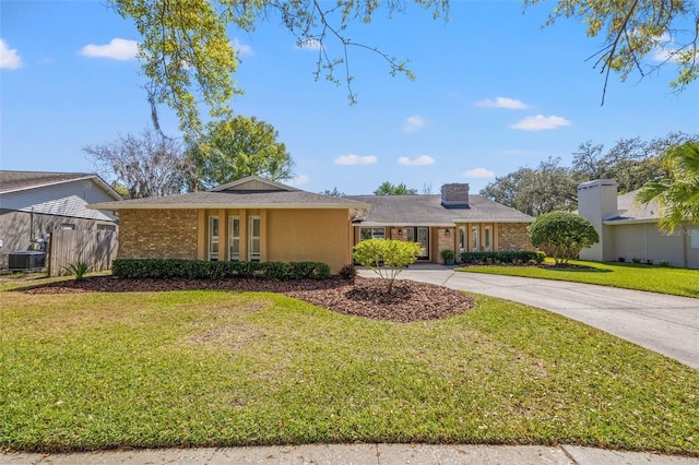 view of front of house with cooling unit, brick siding, driveway, a chimney, and a front yard