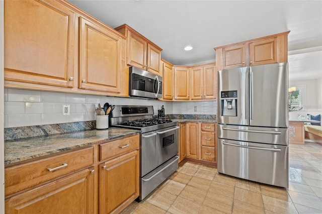 kitchen with appliances with stainless steel finishes, recessed lighting, backsplash, and dark stone countertops