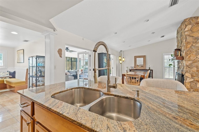 kitchen with decorative columns, a wealth of natural light, visible vents, open floor plan, and a sink