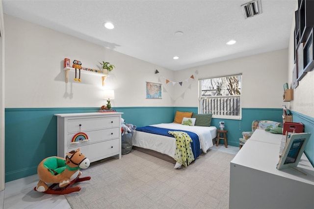 bedroom with a wainscoted wall, visible vents, and recessed lighting