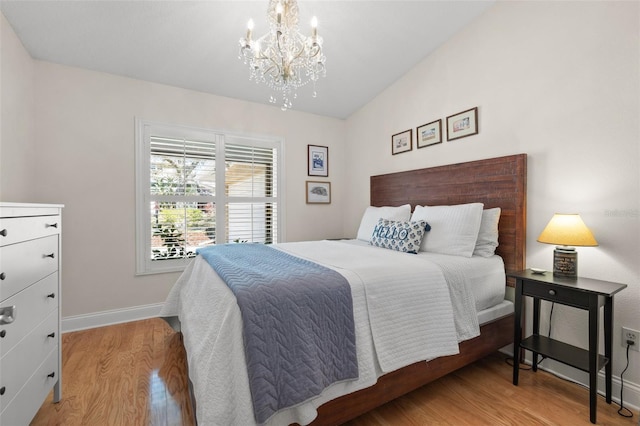 bedroom featuring a chandelier, vaulted ceiling, baseboards, and wood finished floors