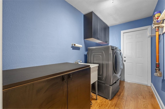 laundry room with light wood-style floors, baseboards, cabinet space, and washing machine and clothes dryer