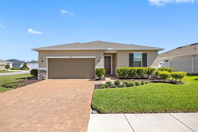 view of front of property with an attached garage, roof with shingles, decorative driveway, stucco siding, and a front lawn