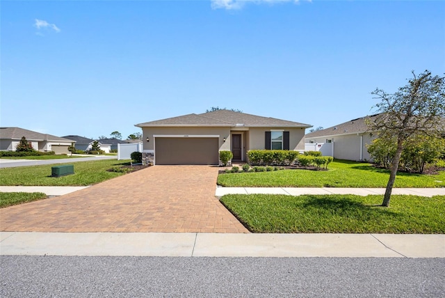 view of front of property featuring a garage, decorative driveway, a front yard, and stucco siding