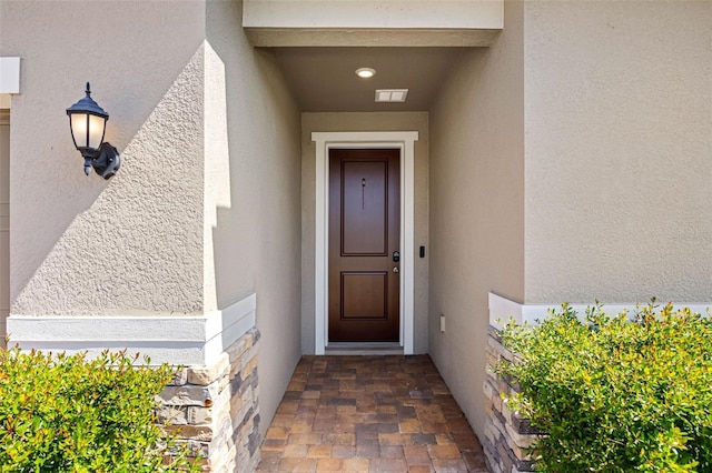 property entrance featuring visible vents and stucco siding