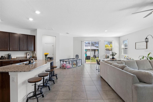 living room with light tile patterned floors, visible vents, ceiling fan, a textured ceiling, and recessed lighting