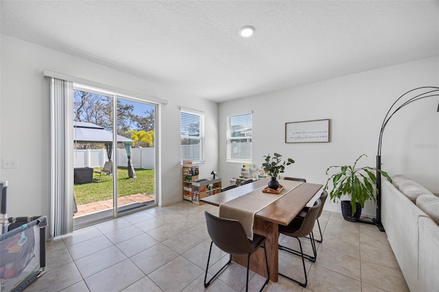 dining room featuring light tile patterned flooring, a textured ceiling, and baseboards