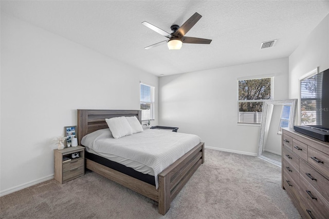 bedroom with a textured ceiling, baseboards, visible vents, and light colored carpet