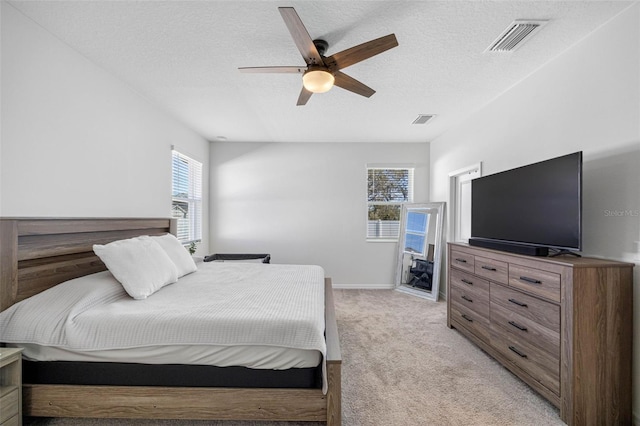 bedroom with ceiling fan, visible vents, a textured ceiling, and light colored carpet