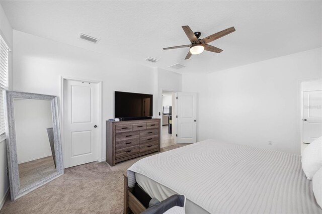 bedroom featuring light colored carpet, visible vents, and ceiling fan