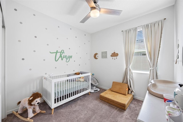 bedroom featuring carpet floors, a nursery area, ceiling fan, and baseboards