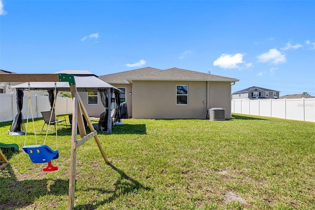 view of yard with a fenced backyard, central AC unit, and a playground