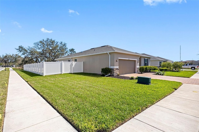 view of property exterior featuring a yard, decorative driveway, fence, and stucco siding