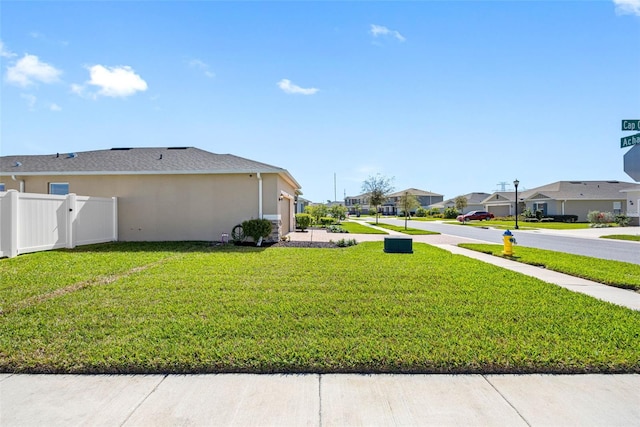 view of yard with a garage, a residential view, and fence