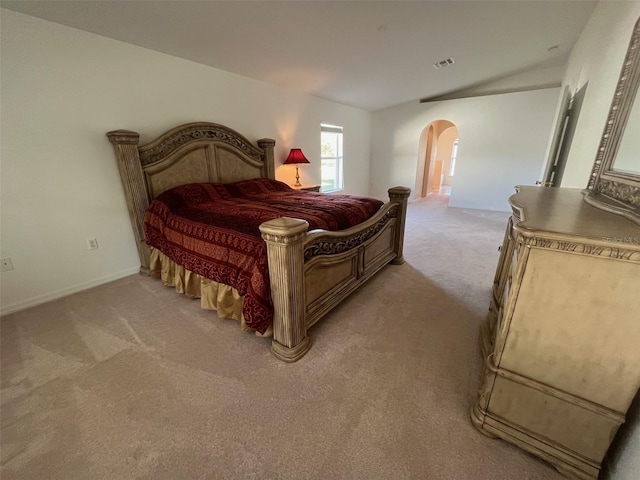 bedroom with light carpet, visible vents, arched walkways, baseboards, and lofted ceiling