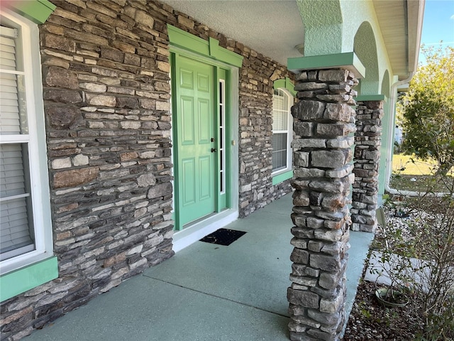 property entrance with a porch and stone siding