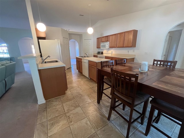 kitchen with arched walkways, white appliances, light countertops, and a sink