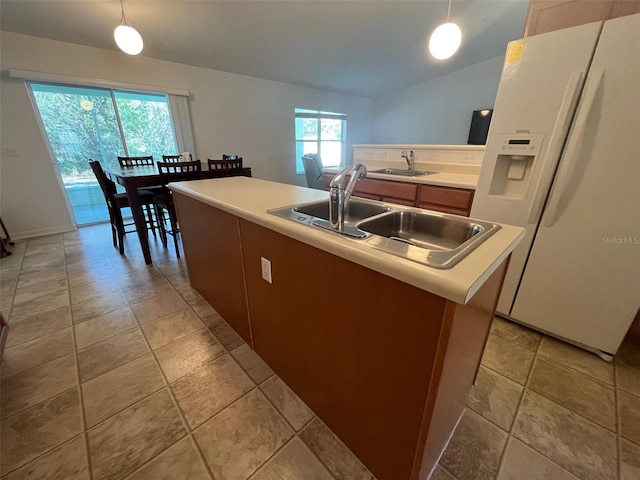 kitchen with white fridge with ice dispenser, vaulted ceiling, light countertops, a sink, and decorative light fixtures