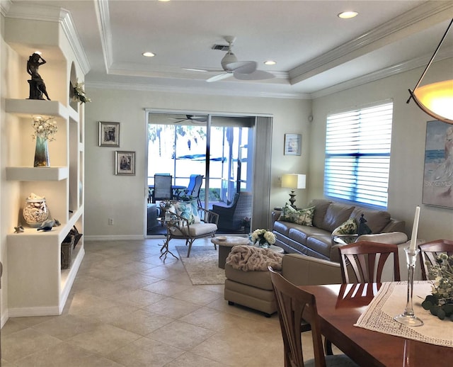 living room with crown molding, a tray ceiling, and a healthy amount of sunlight