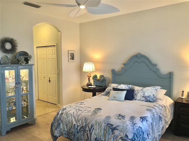 bedroom with visible vents, arched walkways, a ceiling fan, light wood-style floors, and a closet