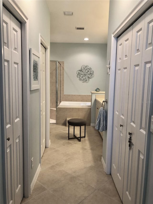 hallway with visible vents, baseboards, and tile patterned floors