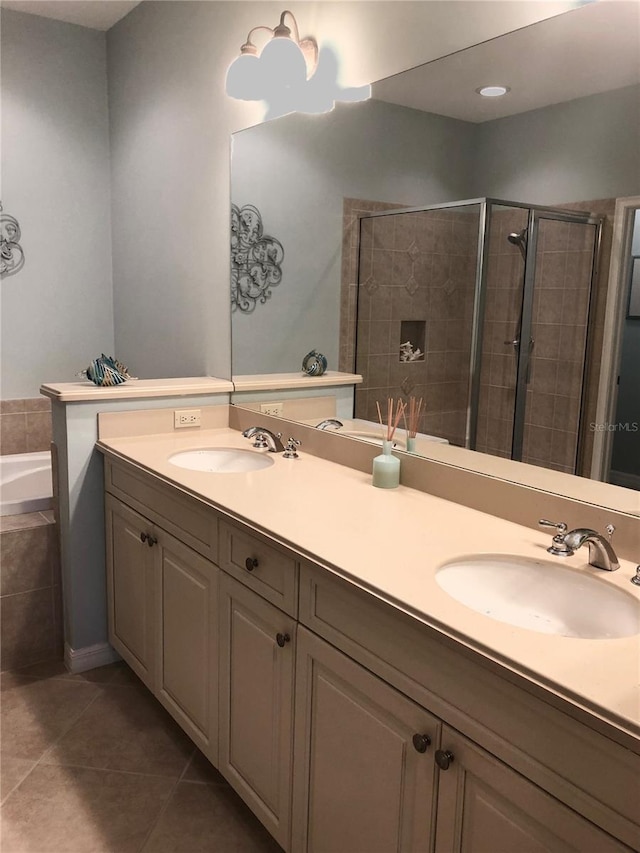 full bath with double vanity, a stall shower, tile patterned flooring, and a sink