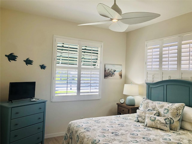 bedroom with ceiling fan, baseboards, and wood finished floors