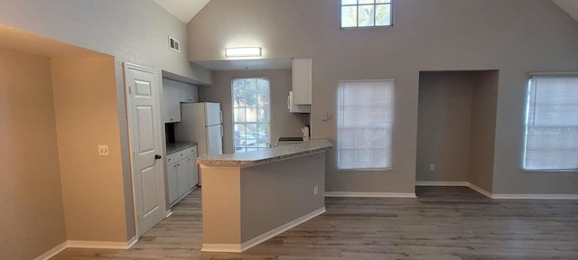 kitchen with visible vents, baseboards, light wood-style flooring, freestanding refrigerator, and light countertops