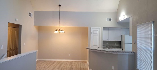 kitchen featuring visible vents, high vaulted ceiling, and freestanding refrigerator