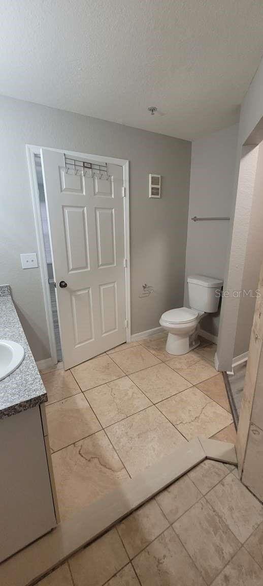 bathroom featuring baseboards, vanity, toilet, and a textured ceiling