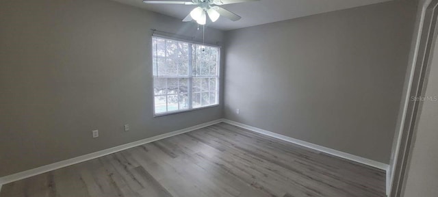 unfurnished room with wood finished floors, a ceiling fan, and baseboards