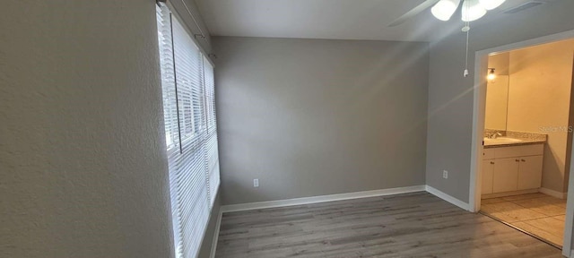 unfurnished bedroom with baseboards, visible vents, ensuite bath, light wood-style flooring, and a sink