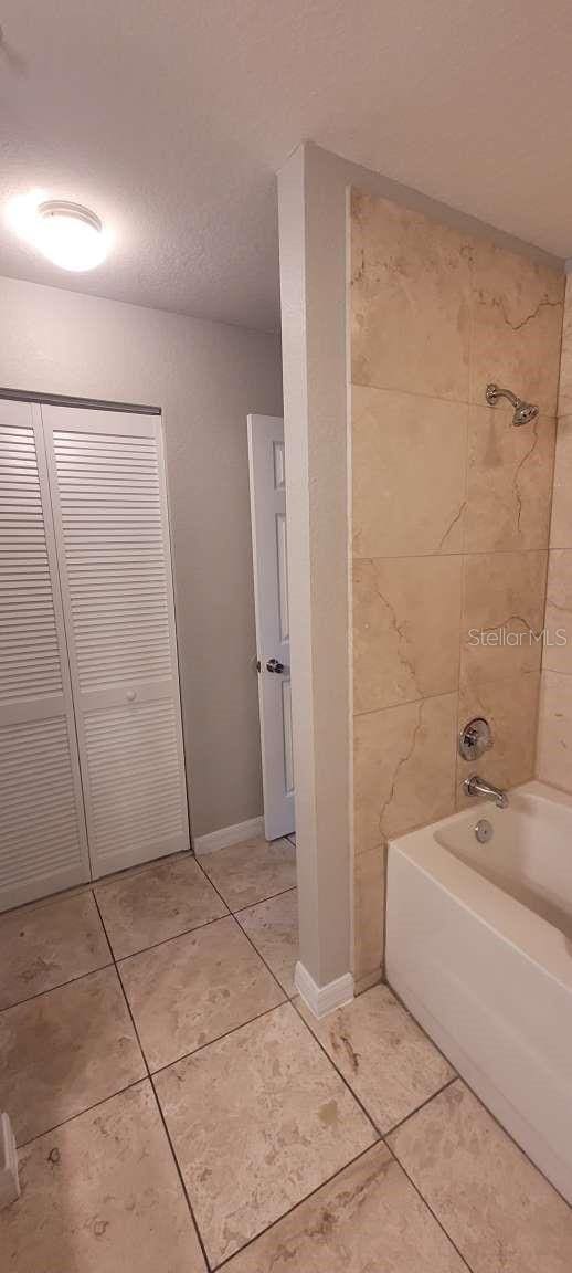 full bathroom with shower / bath combination, tile patterned flooring, and baseboards