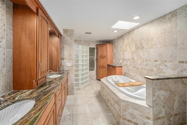 full bathroom featuring double vanity, a skylight, a sink, and tile walls